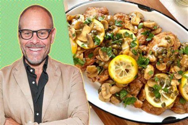 Alton Brown, who has fried chicken tips, smiles wearing a suit and tie