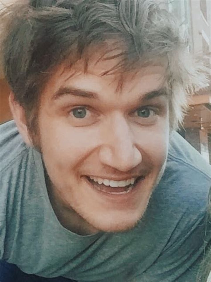 Bo Burnham smiling in front of a gray background