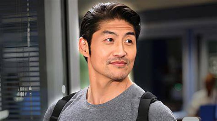 Brian Tee as Ethan Choi in Chicago Med Season 7. Choi is wearing a back brace and standing in front of a monitor.