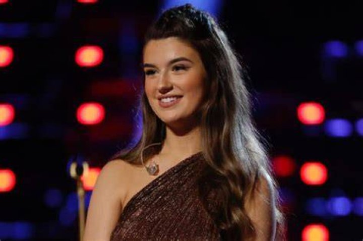 Grace West, a contestant in 'The Voice' Season 23 finale, singing in a purple dress on stage