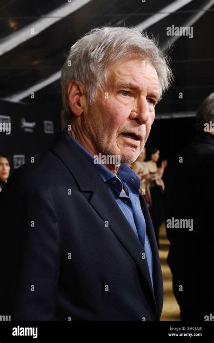 Harrison Ford attends the Los Angeles premiere of 1923 wearing a navy blazer and collared blue shirt.