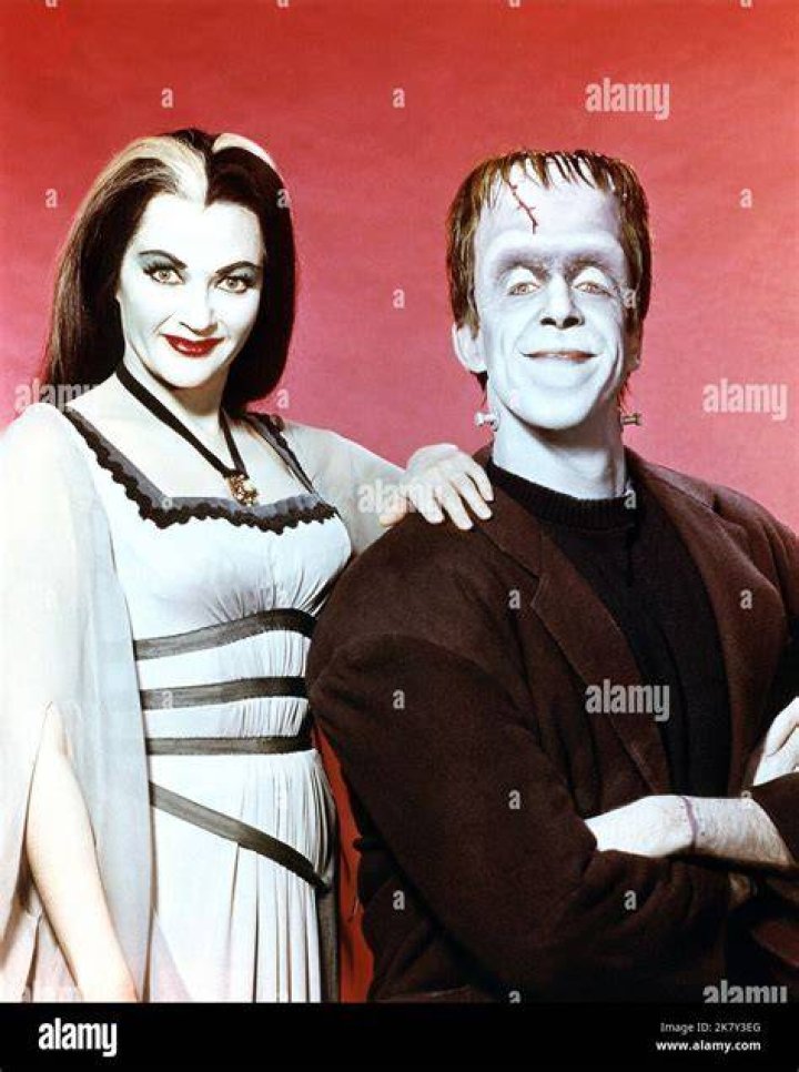 Herman and Lily Munster from 'The Munsters' in front of a cabinet