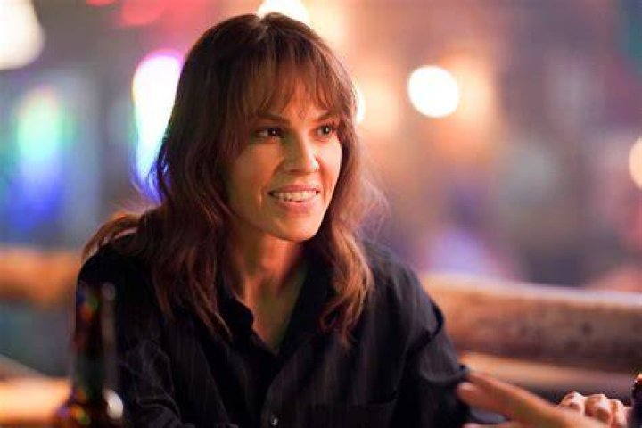 Hilary Swank as Eileen Fitzgerald, who appears in 'Alaska Daily' Episode 7 on ABC, wears a black button-up shirt while pinning a picture to a crime board.