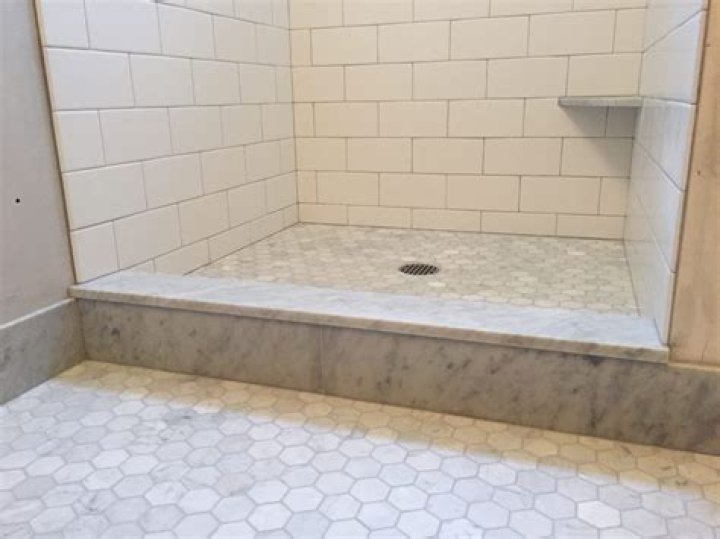 How much should a shower curb overhang?