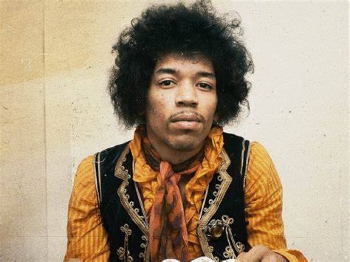Jimi Hendrix, who formed a band called The Kasuals while in the army, performing in front of an American flag