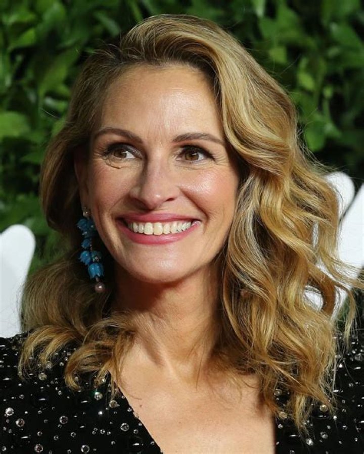 Julia Roberts smiling in front of a green background