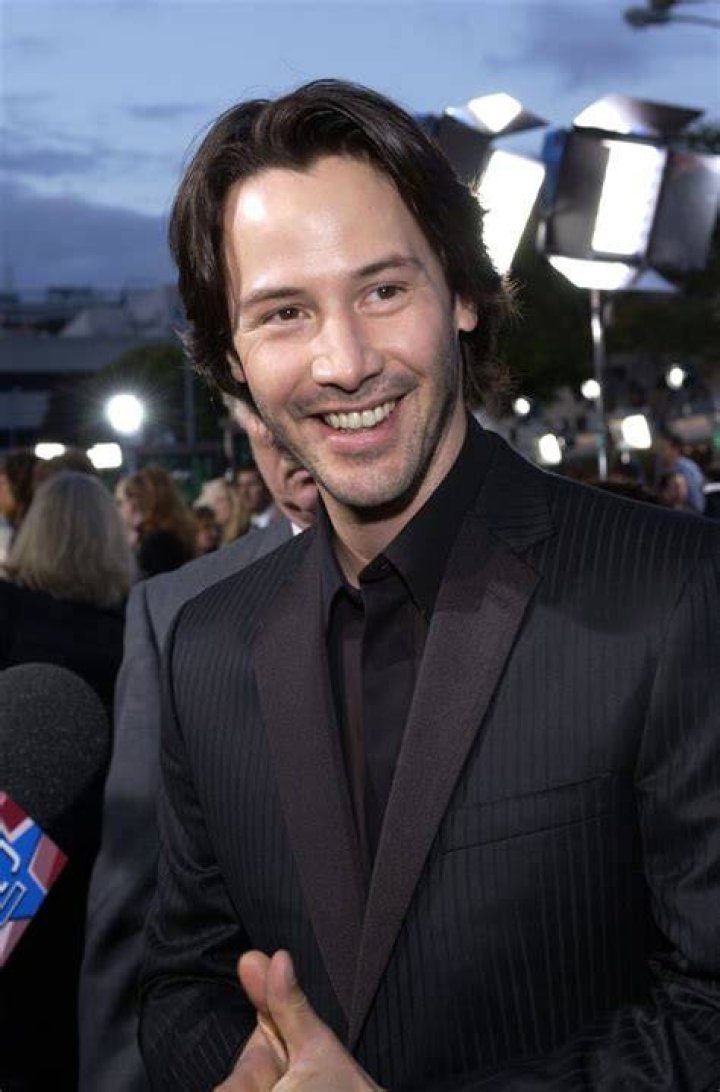 Keanu Reeves smiling in front a white background at the 2020 Oscars