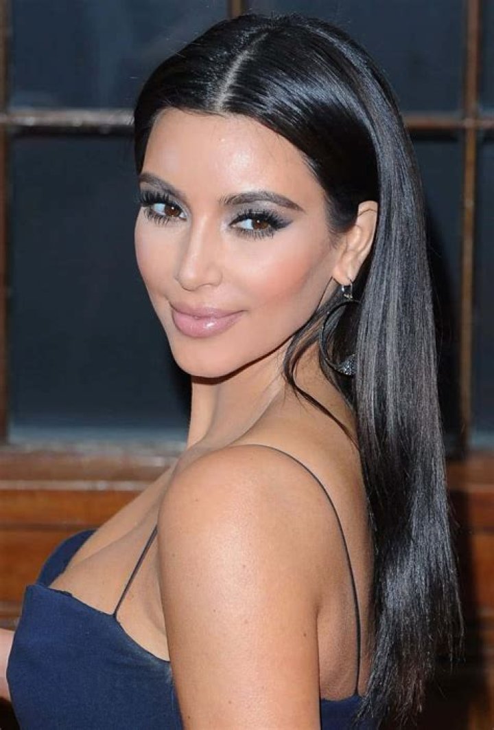 Kim Kardashian looking on in front of a black background