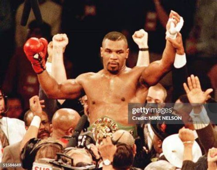 Mike Tyson is lifted into the air wearing the championship belt after defeating WBC heavyweight champion Frank Bruno