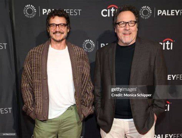 Pedro Pascal and John Favreau pose with several Mandalorians in front of a "The Mandalorian" backdrop.