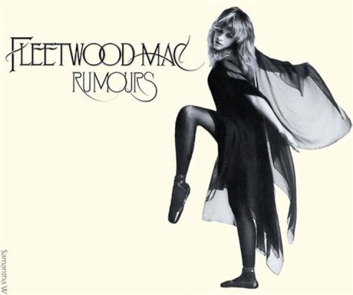 Stevie Nicks poses in front of a red wall.