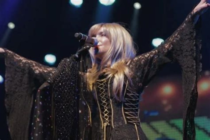 Stevie Nicks sings into a microphone on stage.